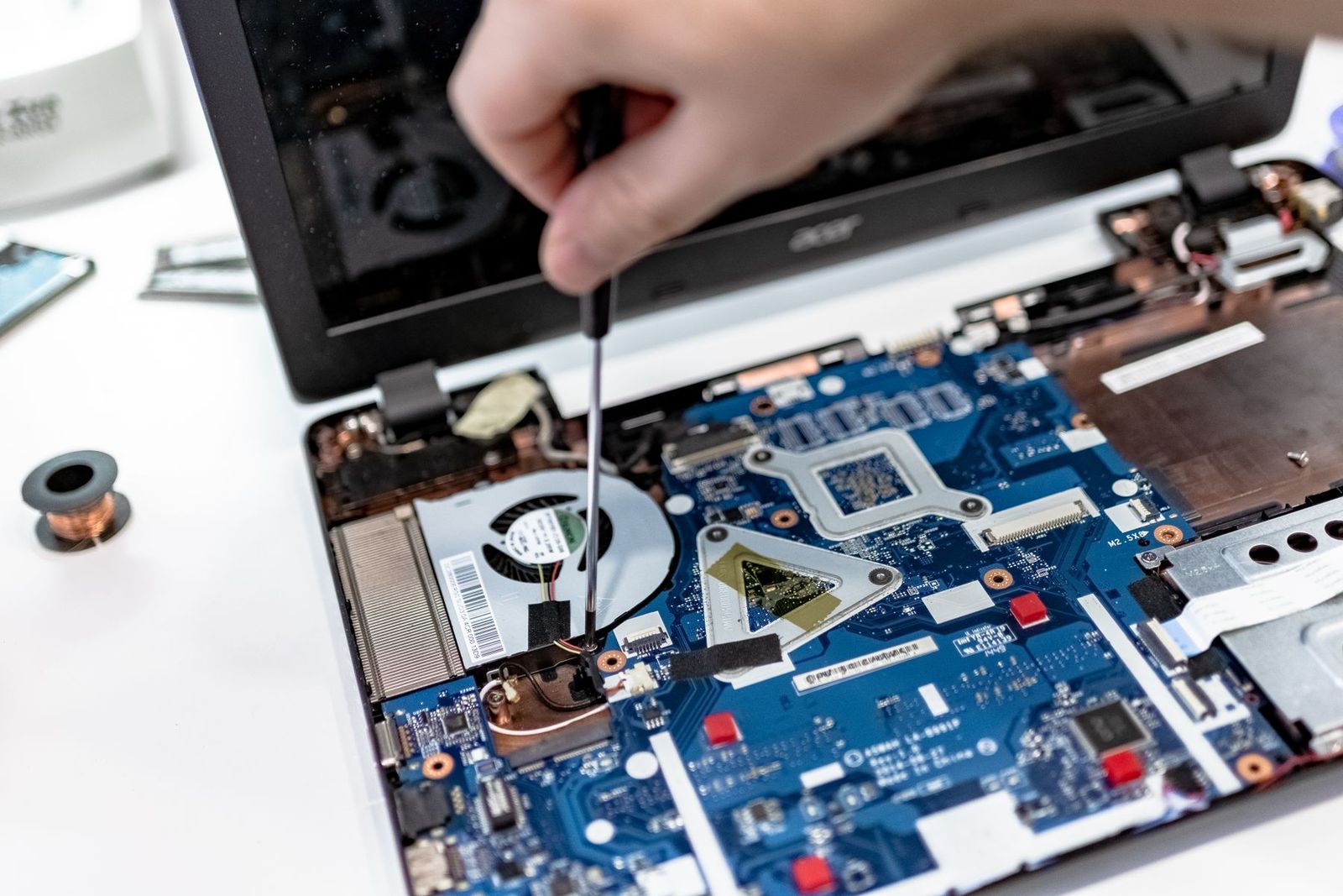 Mão consertando a placa-mãe de um notebook com chave de fenda