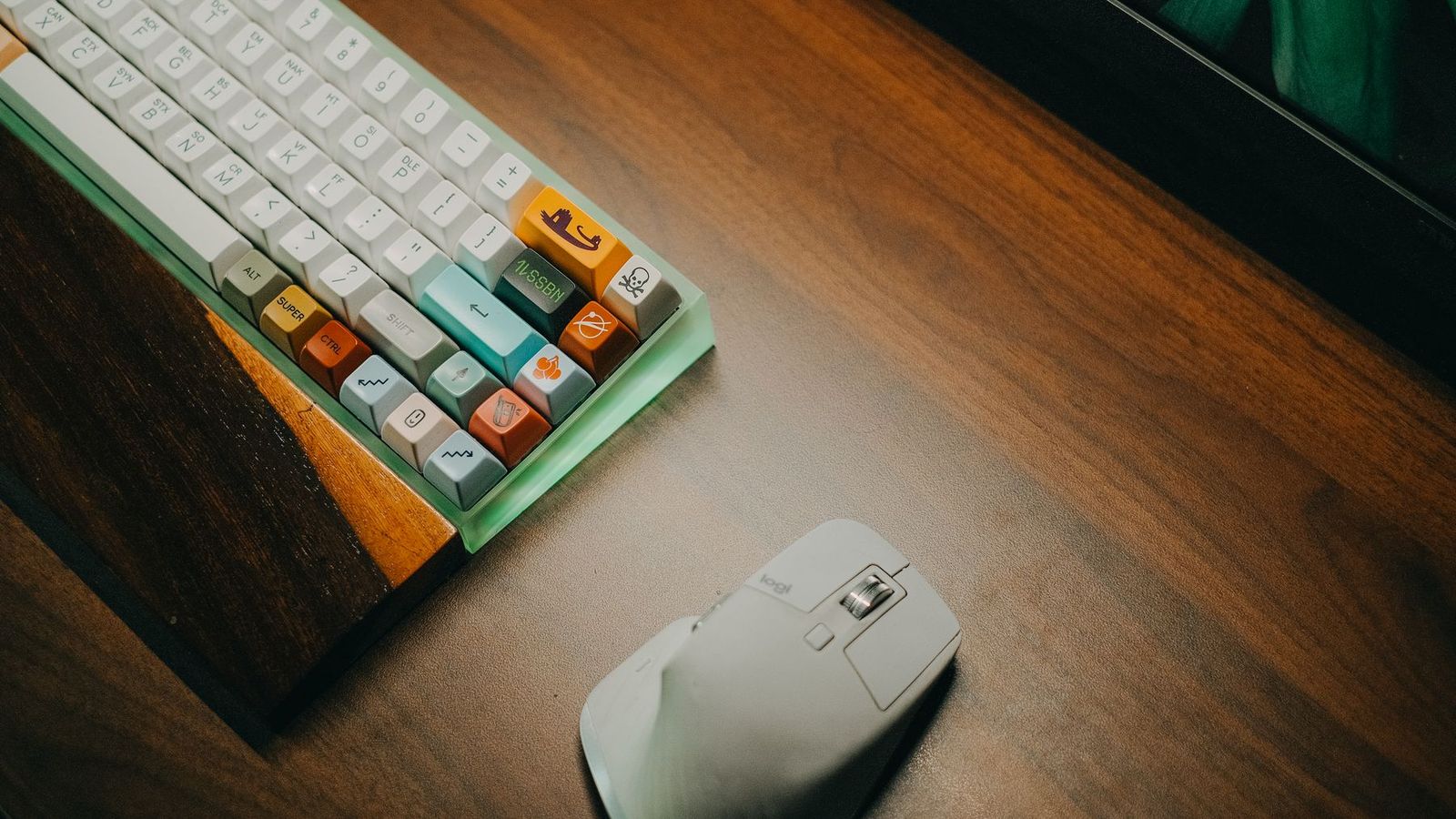 Teclado mecânico colorido e mouse branco em mesa de madeira
