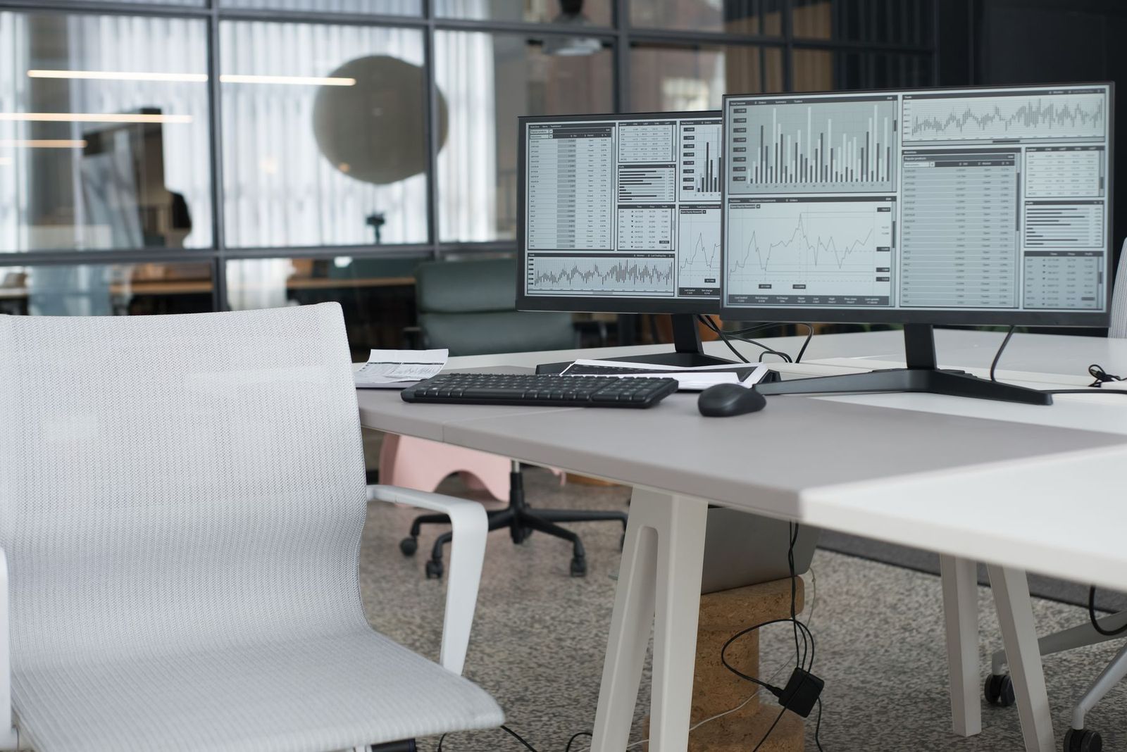 Mesa de escritório com dois monitores de dados e cadeira ergonômica